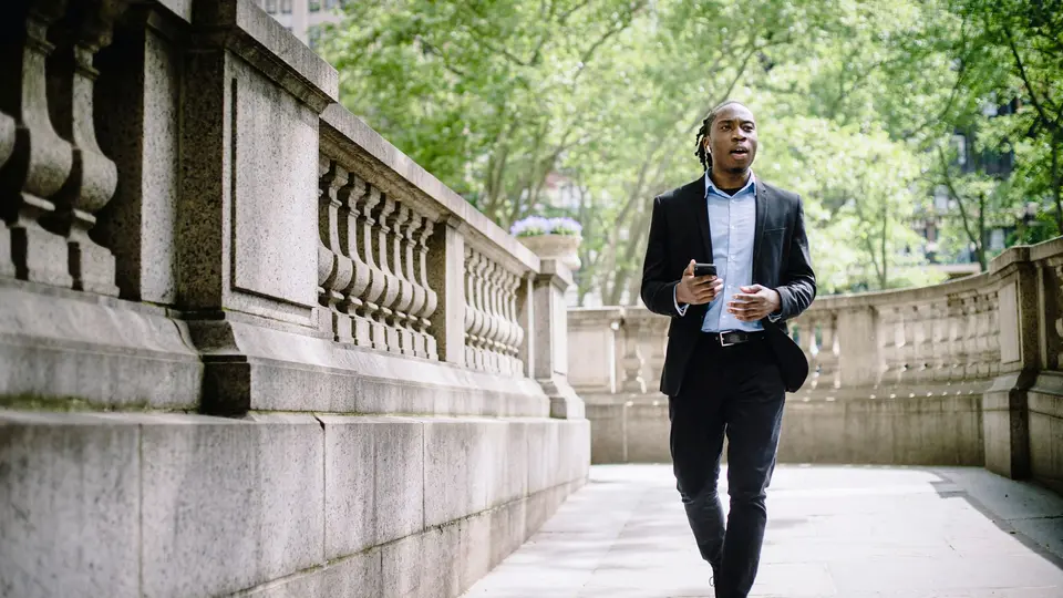 Young professional confidently walking into modern financial district at golden hour