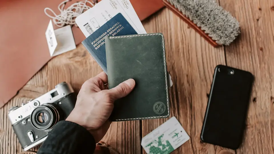 Passport, boarding passes, and slim laptop arranged on wooden airport lounge table