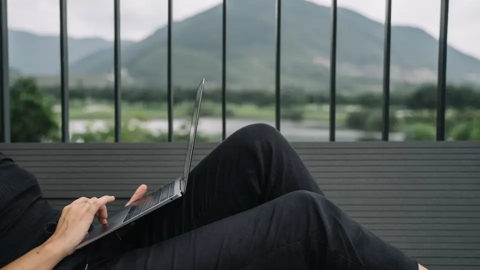 Smiling indie founder working remotely from scenic mountain cabin terrace