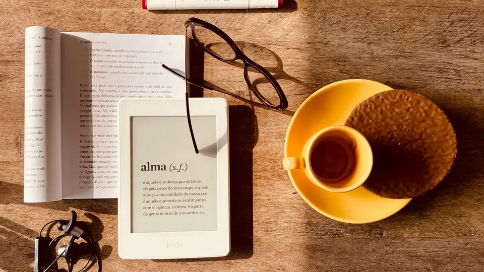 Monochrome e-ink tablet and ceramic coffee cup sitting on uncluttered studio table
