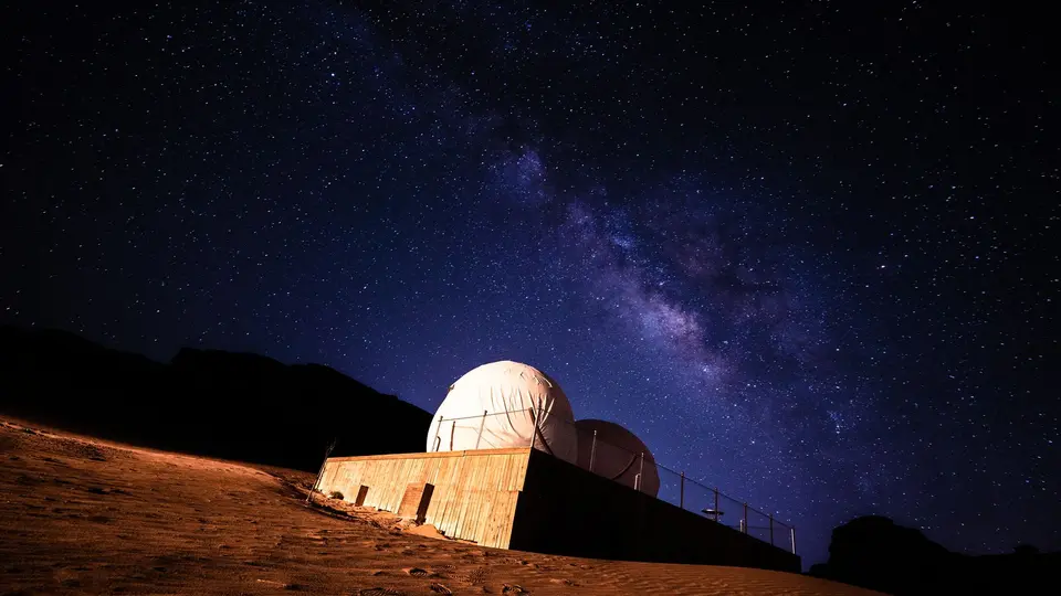 Astronomy telescope pointing at star-filled night sky with glowing milky way