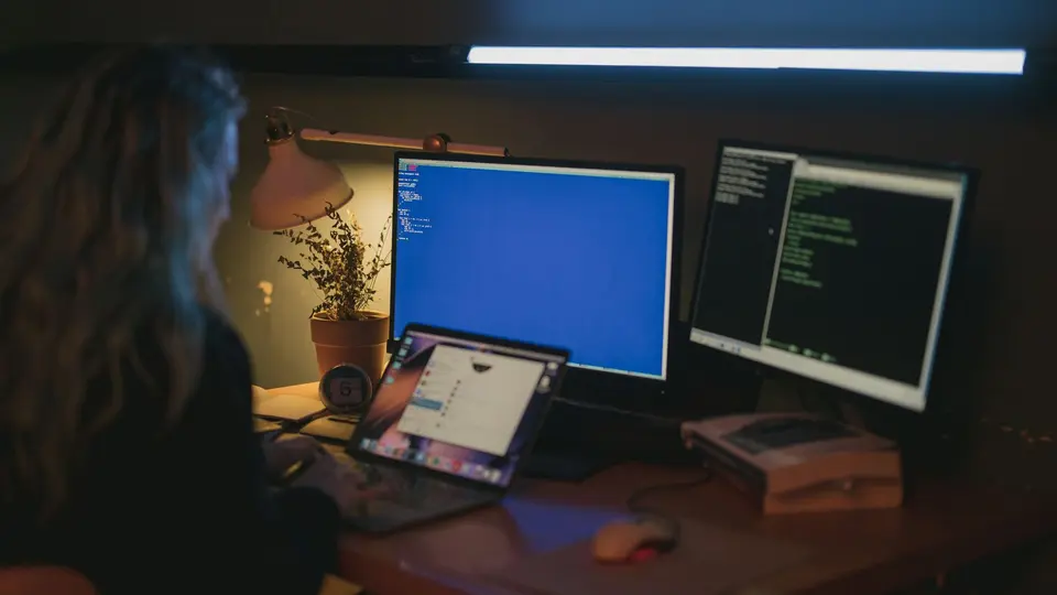 Investigator's desk covered in encrypted printouts, server logs, and cold case folders